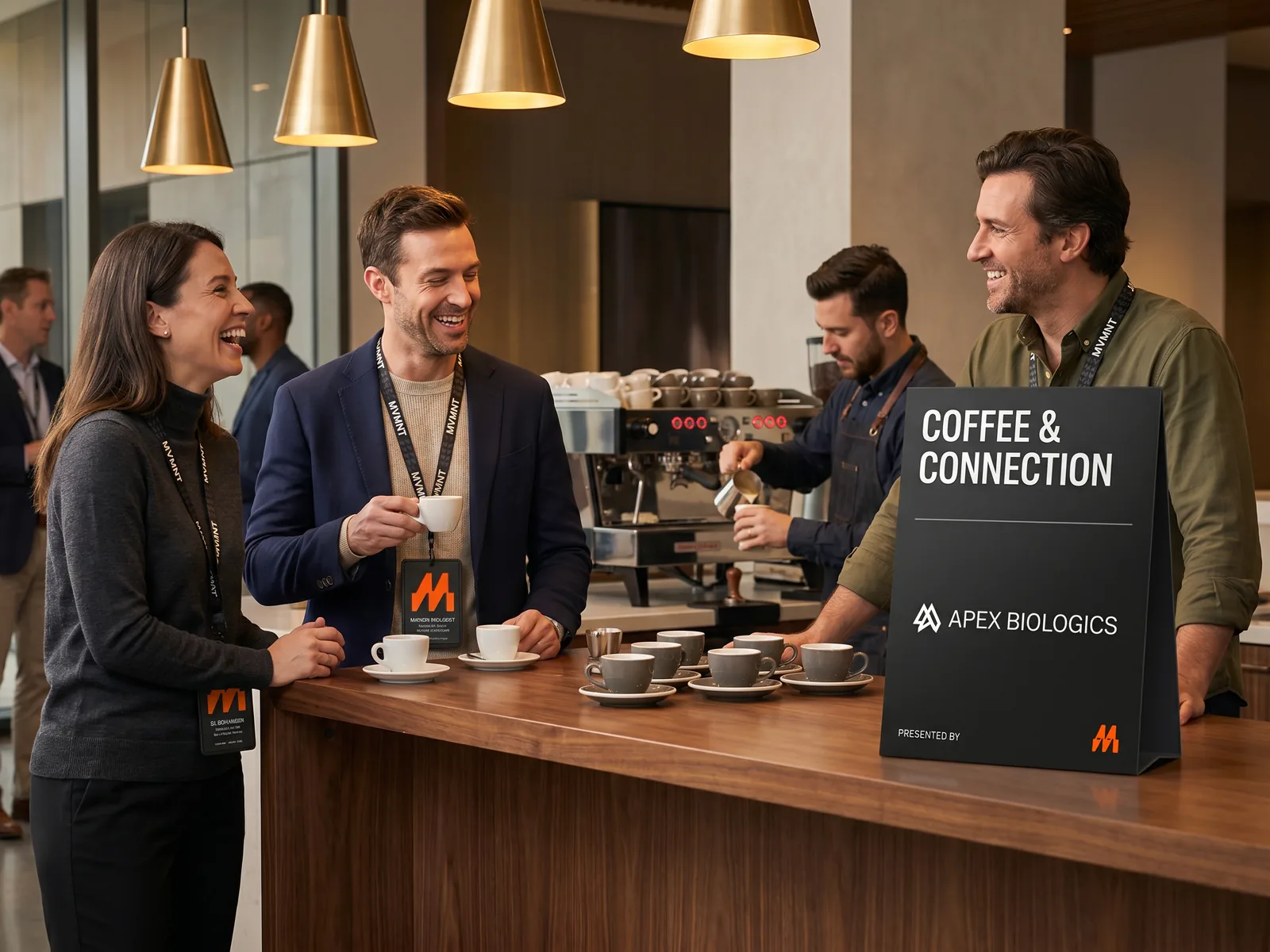 A hosted coffee bar at MVMNT, three attendees laughing at the counter, co-branded tent card on the bar.