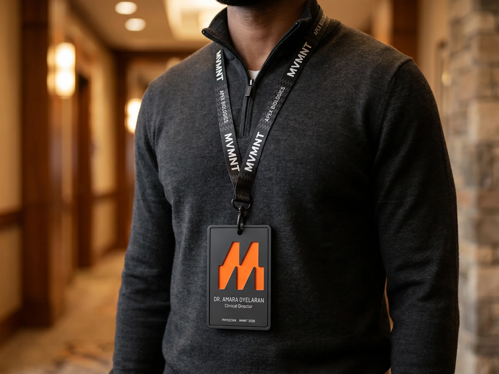A worn MVMNT lanyard with alternating MVMNT and sponsor wordmarks on the cord, canonical badge below.