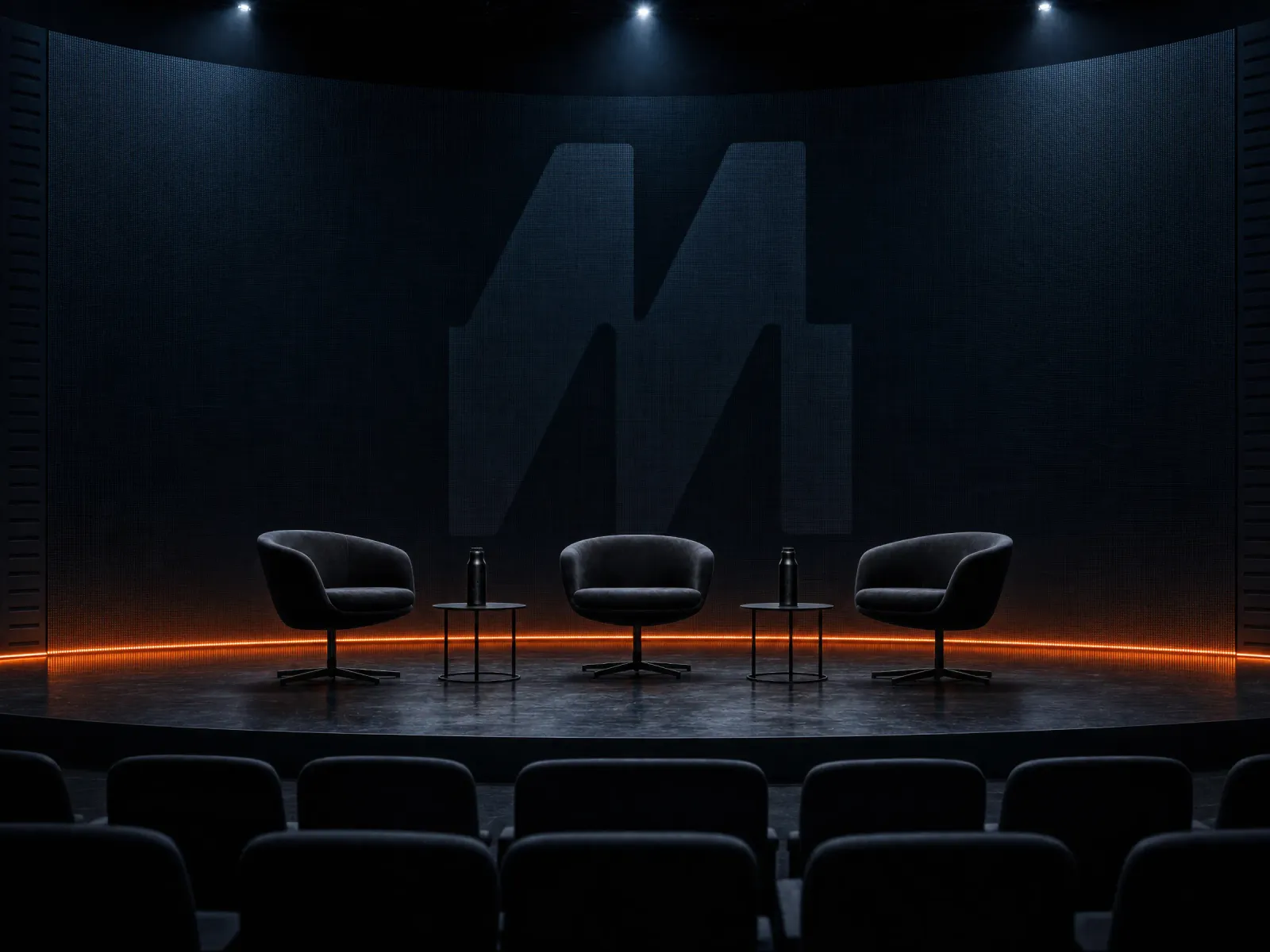 A speaker walks the MVMNT mainstage during a session. The dark backdrop carries a large MVMNT monogram.