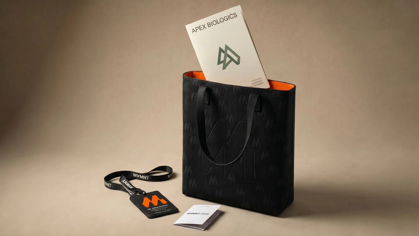 An MVMNT canvas tote with embossed monogram, partner brochure tucked inside as a bag insert.